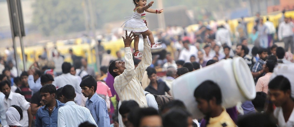 A child lifting a toddler aloft amidst a sea of people