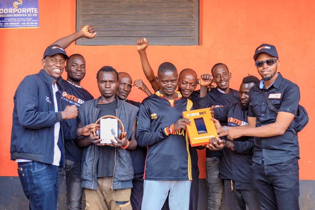 John Nanyumba (L) and Alex Muhangi (R) handing over headsets and a phone in a picture with T-shirts winners at Kikyusa