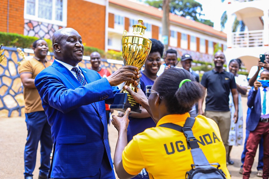 Dr Lawrence Mulindwa recieves a trophy from one of their students