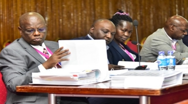 UCAA's Fred Bamwesigye (L) peruses a file as he and other officials appeared before Cosase
